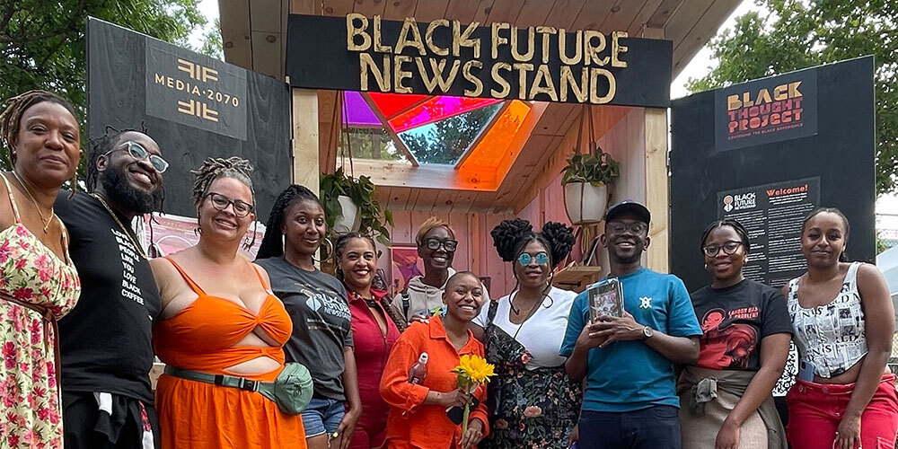 Organizers and supporters standing in front of the Black Future Newsstand installation