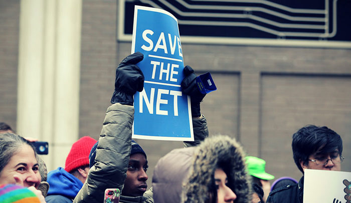 Activist holding sign reading “Save the Net”